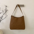 Close-up of caramel brown matte leather bucket bag with minimalist gold metal bar detail - Brown