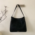 Detail view of black faux suede bucket bag featuring sleek metal trim decoration - Black