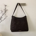 Detail of dark brown suede bucket bag with gold metal plaque on clean white wall background - Brown