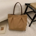 Detail shot of khaki canvas tote bag with pleated design and brown leather straps on a chair - Caramel color