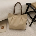 Detail view of a beige canvas tote bag with brown PU leather handles in a cozy home setting - Khaki