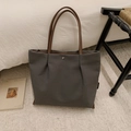 Detail of grey canvas tote bag with brown handles and silver decorative buckle on a rug - Dark Brown
