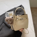 Vue détaillée du sac seau en cuir beige avec boucle argentée et breloque lapin en peluche - Avec Pendentif / Blanc