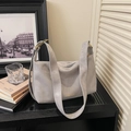 Close-up of grey suede tote bag featuring golden hardware and fashion logo detail - Gray
