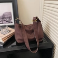Detail of a dark brown suede tote bag featuring a wide shoulder strap and golden metal buckle - Coffee