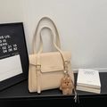 Detail of beige lychee pattern tote bag with gold buckle and brown plush bear charm - With Charm / Off White