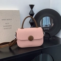 Detalle de bolso rosa texturizado con hebilla decorativa redonda grande y asa superior marrón - Rosa