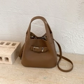 Brown leather bucket bag with silver buckle and adjustable strap shown on marble base - Brown No Pendant