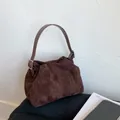Detalle del bolso de ante marrón oscuro con forma de media luna, pliegues y correa ajustable - Marrón