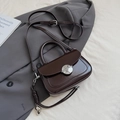 Elegante schokoladenbraune Satteltasche mit silberner Schnalle und geflochtenem Anhänger - Mit Anhänger / Braun