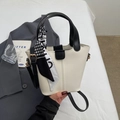 Detail der cremefarbenen Beuteltasche mit schwarzen Griffen und einem Hahnentritt-Seidentuch - Weiß und Schwarz