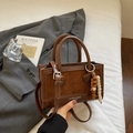 Détail d'un sac à main patchwork marron avec pendentif en perles sur fond épuré - Style d'Épissage en Daim (Avec Charme) / Brun Épissage Suédé Avec Charme