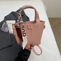 Detailaufnahme der rosa Eimertasche mit Textur und stilvollem Seidenschal am Taschengriff - Rosa