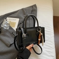 Sac Boston noir chic avec charm en perles de bois dans un décor professionnel moderne - Noir avec pendentif