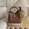 Detail of a brown lychee pattern leather handbag with a silver turn-lock on a wooden table - Brown