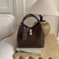 Detailed texture of brown pebble leather bucket bag with silver twist lock on books - Brown