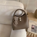 Macro shot of brown pebble grain leather bucket bag with silver metal swivel lock - Gray