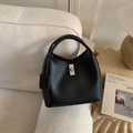 Detail of black pebbled leather bucket bag with silver twist lock and burgundy lining - Black