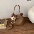 Détail d'un sac seau marron en cuir grainé avec pendentif chien sur une table en bois - Marron (Avec Pendentif)