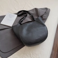Minimalist black pebble leather hobo bag with adjustable silver buckle on white fabric - Black