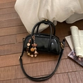 Detail einer schwarzen glänzenden Bowling-Tasche mit Perlenanhänger auf Holzboden - Schwarz mit Anhänger