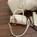 Detailansicht der cremefarbenen Handtasche mit Perlenanhänger und Gold-Hardware - Beige Mit Anhänger