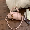Rosa Zylindertasche mit Bärenanhänger und verstellbarem Gurt auf dunklem Holzboden - Roze mit Anhänger