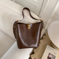 Borsa a secchiello in pelle testa di moro con chiusura dorata su divano beige - Marrone Senza Ciondolo