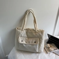 Minimalist beige quilted puffer tote bag with black contrast snaps in a cozy lifestyle setting - Off-white