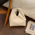 Dettaglio della borsa in pelle color crema con trama litchi e manico annodato di design - Bianco
