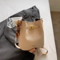 Beige faux leather bucket bag with gold lock and wooden bead charm on a grey suit jacket - Beige With Charm
