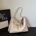 Detail view of a large cream faux leather tote bag with stylish long straps and tassel - White With Charm
