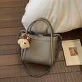 Detail of grey lychee leather bucket bag with plush dog charm and cylinder handle - With Charm / Gray