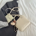 Borsa a secchiello beige in pelle con ciondolo a orsetto e tracolla regolabile - Bianco