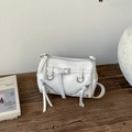 Detail view of white PU leather pillow bag with metal buckles and zipper accents - White