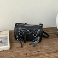 Detail of black glossy leather cylinder bag with silver zippers and long tassels on wood - Black