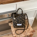 Dettaglio borsa a tracolla leopardata su sedia in legno con ciondolo a forma di cuore - Marrone con ciondolo