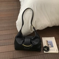 Nahaufnahme der schwarzen Ledertasche mit goldener Verzierung und modischen Falten - Schwarz