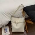 Dettaglio della borsa a secchiello in pelle crema con fibbia decorativa sul divano - Bianco