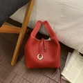 Macro detail of red lychee texture bucket bag with silver ring hardware and drawstring - Red