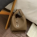 Close-up of brown pebbled leather bucket bag with metal ring and crossbody strap - Brown