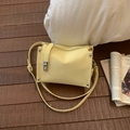 Close-up of yellow faux leather crossbody bag with metal rivets and wrinkled texture - Yellow