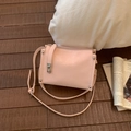 Detail of light pink textured crossbody bag with silver twist lock and rivet accents - Pink