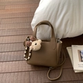 Close-up of brown lychee leather handbag with adjustable strap and cute bear charm - Brown with Pendant