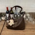 Detail view of brown vintage soft leather tote bag with white plush alpaca charm on wood table - Coffee with Pendant