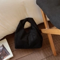 Detail of minimalist black pleated hobo bag in faux suede on a wooden chair - Black