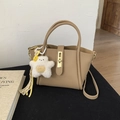 Detail view of camel leather bucket bag with gold clasp and plush bear charm - With Charm / Khaki
