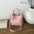 Detailed close-up of light pink lychee grain leather bucket bag on a wooden table - Pink