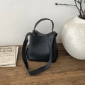 Detail of black pebbled leather bucket bag with top handle and wide shoulder strap - Black