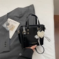 Glossy black bucket bag with a pearl heart charm and adjustable shoulder strap for women - Black With Pendant